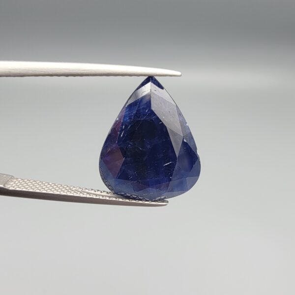 A 13.18-carat natural deep blue Sapphire from Afghanistan, master-faceted into a pear shape and displayed in a professional gemstone box.