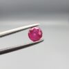 A 0.43-carat natural red Ruby (Yaqoot) from Kabul, Afghanistan, featuring a round cut with visible natural mountain cracks and surface textures, held in jeweler's tweezers.