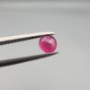 A 0.43-carat natural red Ruby (Yaqoot) from Kabul, Afghanistan, featuring a round cut with visible natural mountain cracks and surface textures, held in jeweler's tweezers.