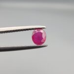 ​A 0.47-carat natural red Ruby (Yaqoot) from Kabul, Afghanistan, featuring an oval faceted cut with rich red color and natural inclusions, held in jeweler's tweezers.