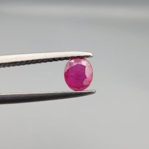 ​A 0.47-carat natural red Ruby (Yaqoot) from Kabul, Afghanistan, featuring an oval faceted cut with rich red color and natural inclusions, held in jeweler's tweezers.
