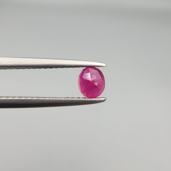 ​A 0.47-carat natural red Ruby (Yaqoot) from Kabul, Afghanistan, featuring an oval faceted cut with rich red color and natural inclusions, held in jeweler's tweezers.