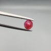 A 0.53-carat natural red Ruby (Yaqoot) from Kabul, Afghanistan, featuring a round brilliant cut with a unique yellow mountain inclusion on the back side, held in jeweler's tweezers.