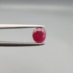 ​A 0.52-carat natural red Ruby (Yaqoot) from Kabul, Afghanistan, featuring an oval faceted cut with saturated red color and natural organic inclusions, held in jeweler's tweezers.