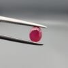​A 0.57-carat natural red Ruby (Yaqoot) from Kabul, Afghanistan, featuring an oval faceted cut with saturated red color and natural organic inclusions, held in jeweler's tweezers.