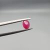 ​A 0.57-carat natural red Ruby (Yaqoot) from Kabul, Afghanistan, featuring an oval faceted cut with saturated red color and natural organic inclusions, held in jeweler's tweezers.