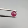 A 0.39-carat natural red Ruby (Yaqoot) from Kabul, Afghanistan, featuring a round brilliant cut with a natural mountain hole on the back and a tiny black inclusion on the front, held in jeweler's tweezers.