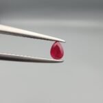 A 0.44-carat natural red Ruby (Yaqoot) from Kabul, Afghanistan, featuring a brilliant pear faceted cut with rich red color and natural organic inclusions, held in jeweler's tweezers.