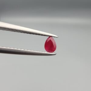 A 0.44-carat natural red Ruby (Yaqoot) from Kabul, Afghanistan, featuring a brilliant pear faceted cut with rich red color and natural organic inclusions, held in jeweler's tweezers.