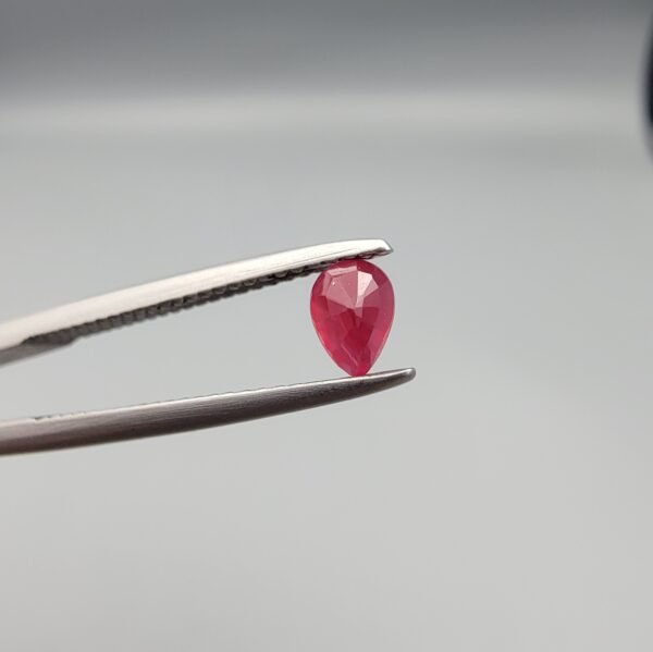 A 0.44-carat natural red Ruby (Yaqoot) from Kabul, Afghanistan, featuring a brilliant pear faceted cut with rich red color and natural organic inclusions, held in jeweler's tweezers.