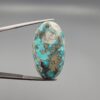 ​A large 45.87-carat natural Turquoise (Feroza) from Kerman, Iran, featuring a bold oval cabochon cut with a heavy golden pyrite matrix and deep blue-green color.