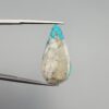 ​A 20.97-carat natural blue-green Turquoise (Feroza) from Kerman, Iran, featuring a pear-shaped cabochon cut with a shimmering golden pyrite matrix, held in jeweler's tweezers.