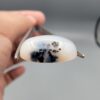 An 8.64-carat natural Iranian Milky Dendritic Agate (Shajari Dudhiya Aqeeq) cabochon with a glowing translucent white body and dark tree-like organic inclusions, held in jeweler's tweezers.