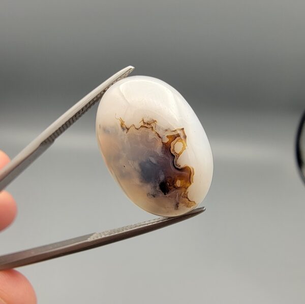 ​A 14.85-carat Iranian Shajari Dudhiya Aqeeq showing a forest of black and brown dendrites on the front and a natural black cloud and storm-like foam design on the back.