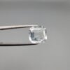 ​A 4-carat natural Shigar Valley Aquamarine (Beruj) gemstone with an octagon emerald cut, displaying a clear sea-blue color and unique natural inclusions, held in jeweler's tweezers.