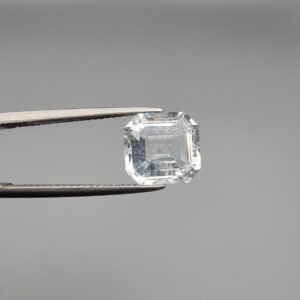 ​A 4-carat natural Shigar Valley Aquamarine (Beruj) gemstone with an octagon emerald cut, displaying a clear sea-blue color and unique natural inclusions, held in jeweler's tweezers.