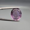 ​A 7.89-carat natural Brazilian Amethyst (Katela) gemstone with an oval faceted cut, featuring a deep purple color and high clarity, held in jeweler's tweezers.