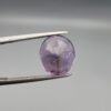​A 7.89-carat natural Brazilian Amethyst (Katela) gemstone with an oval faceted cut, featuring a deep purple color and high clarity, held in jeweler's tweezers.