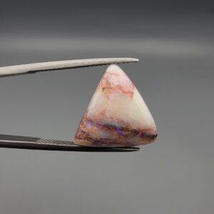 A 14.83-carat natural Australian White Opal with vibrant red, green, and yellow fire, showing unique natural dark and red surface inclusions, held in jeweler's tweezers.