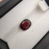 A 2.76-carat natural oval-cut Madagascar Garnet featuring a rich crimson red hue and high-luster facets, displayed in a black jeweler's box.