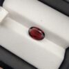 A 2.35-carat natural oval-cut Madagascar Garnet with a deep crimson red hue and high-luster facets, presented in a black jewelry box.