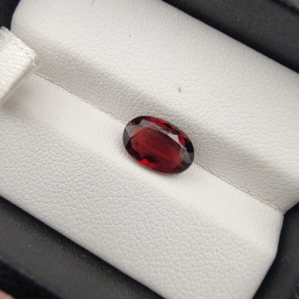 A 2.35-carat natural oval-cut Madagascar Garnet with a deep crimson red hue and high-luster facets, presented in a black jewelry box.