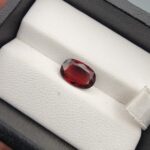 A 2.79-carat natural oval-cut Madagascar Garnet featuring a rich crimson red color and high-clarity facets, presented in a black jewelry box.
