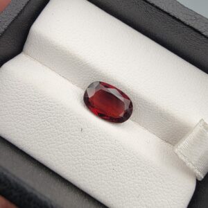 A 2.79-carat natural oval-cut Madagascar Garnet featuring a rich crimson red color and high-clarity facets, presented in a black jewelry box.