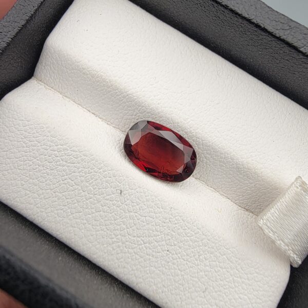 A 2.79-carat natural oval-cut Madagascar Garnet featuring a rich crimson red color and high-clarity facets, presented in a black jewelry box.