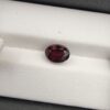 A 2.69-carat natural oval-cut Madagascar Garnet with a deep red color and high-clarity facets, presented in a clear jeweler's display case.