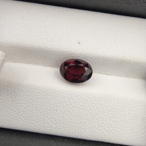 A 2.69-carat natural oval-cut Madagascar Garnet with a deep red color and high-clarity facets, presented in a clear jeweler's display case.