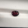 A 2.69-carat natural oval-cut Madagascar Garnet with a deep red color and high-clarity facets, presented in a clear jeweler's display case.