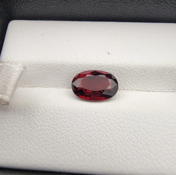 A 2.50-carat natural oval-cut Madagascar Garnet featuring a rich crimson red color and high-clarity facets, presented in a jeweler's display case.