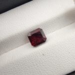 A 2.23-carat natural square-cut Madagascar Garnet with a rich crimson-red color and excellent clarity, shown in a jeweler's display case.