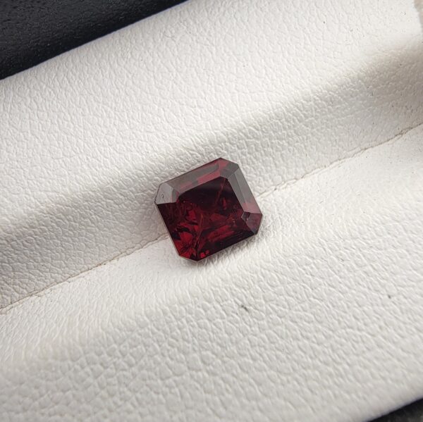 A 2.23-carat natural square-cut Madagascar Garnet with a rich crimson-red color and excellent clarity, shown in a jeweler's display case.