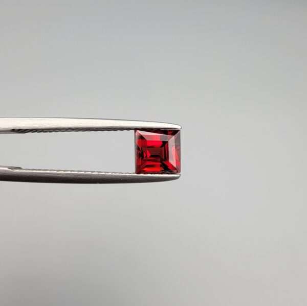 A 1.33-carat natural deep red Madagascar Garnet in a square princess or step cut, showcasing exceptional brilliance and "super sparkling" facets in a clear gemstone display.