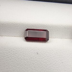 A 2.51-carat natural octagon-cut Madagascar Garnet with a deep red color and sharp geometric facets, presented in a clear jeweler's display case.