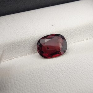 A 3.26-carat natural oval-cut Madagascar Garnet featuring a rich deep red color and high-clarity facets, displayed in a gemstone case.