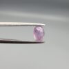 A 0.65-carat natural Ceylon purple sapphire featuring unique black mountain-desert inclusions and an oval faceted cut, displayed in a white jeweler's box.