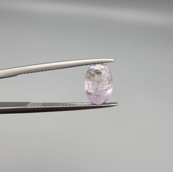 A 2.38-carat natural Ceylon purple sapphire with unique internal mountain-desert inclusions and an oval faceted cut, displayed in a white jeweler's box.