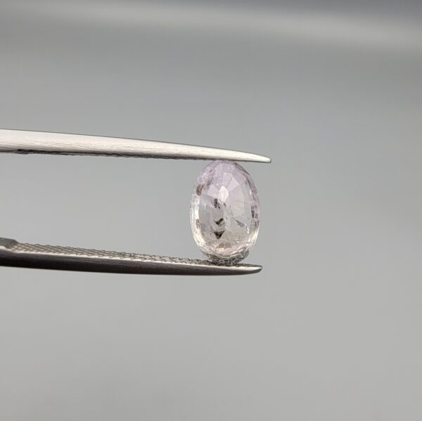 A 2.38-carat natural Ceylon purple sapphire with unique internal mountain-desert inclusions and an oval faceted cut, displayed in a white jeweler's box.