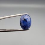 ​A massive 7.54-carat natural Ceylon blue sapphire with a deep royal blue color and oval faceted cut, shown in a professional jeweler's display box.