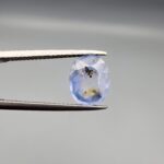 A 2.17-carat natural Ceylon blue sapphire with unique internal black and yellow inclusions, featuring an oval faceted cut and transparent blue body.