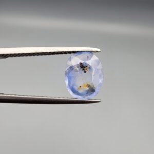 A 2.17-carat natural Ceylon blue sapphire with unique internal black and yellow inclusions, featuring an oval faceted cut and transparent blue body.