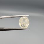 A 3.05-carat natural Ceylon yellow sapphire with transparent clarity and golden internal inclusions, featuring an oval faceted cut, displayed in a white jeweler's box.