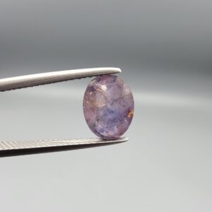 ​A 2.96-carat natural Ceylon purple sapphire with a transparent violet-purple color and oval faceted cut, shown in a white jeweler's box under professional lighting.