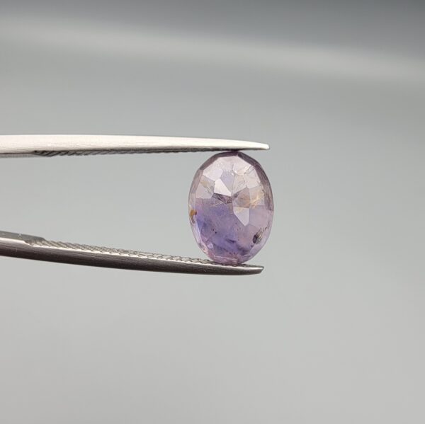 ​A 2.96-carat natural Ceylon purple sapphire with a transparent violet-purple color and oval faceted cut, shown in a white jeweler's box under professional lighting.
