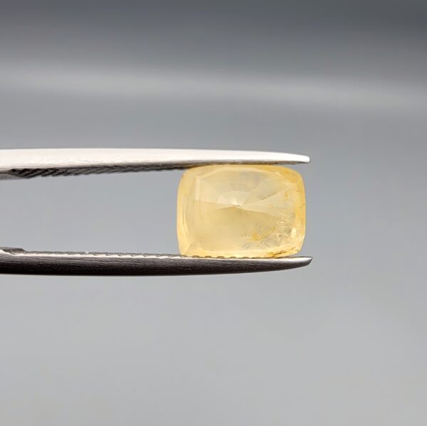 A 3.14-carat natural Ceylon yellow sapphire with a cushion faceted cut and visible golden internal inclusions, presented in a white jeweler's box.
