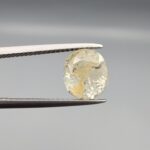 ​A 4.39-carat natural Ceylon yellow sapphire with transparent clarity and golden internal inclusions, featuring an oval faceted cut, displayed in a white jeweler's box.