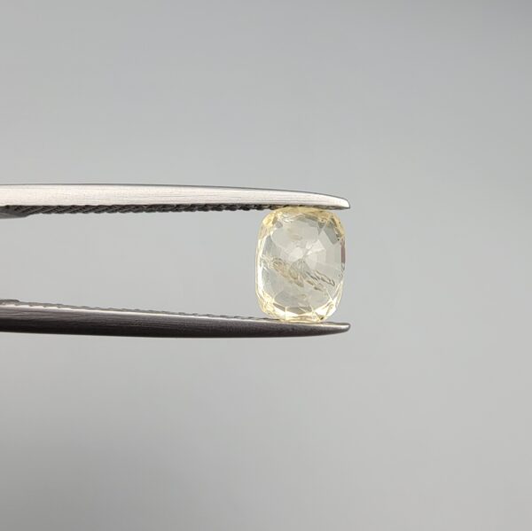 ​A 1.68-carat natural yellow sapphire from Sri Lanka (Ceylon) with a cushion faceted cut, displaying a bright canary yellow color and high transparency, presented in a white jeweler's box.